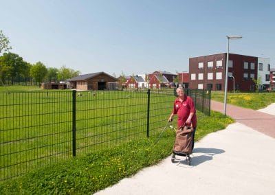Vrouw ruimt rommel op rondom Dierenweide Zodiak met een prikstok en een karretje