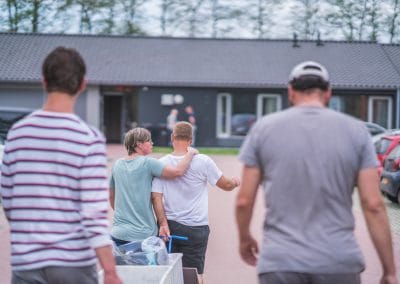 2 mannen lopen achter een andere man die een arm om zijn schouder heeft van een vrouw