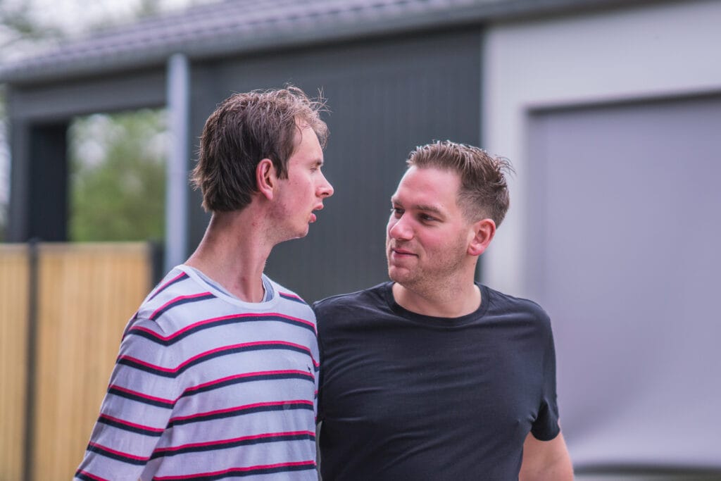 Twee jonge mannen kijken elkaar aan gestreepte trui en zwart tshirt