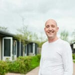 Lachende man in witte trui grijs zwarte gebouwen